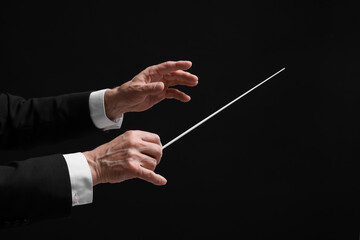Professional conductor with baton on black background, closeup - obrazy, fototapety, plakaty