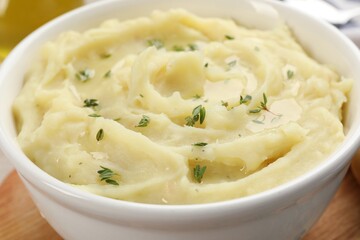 Bowl of tasty mashed potato with rosemary on wooden table, closeup
