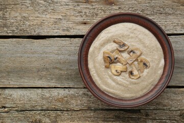 Fototapeta na wymiar Delicious mushroom cream soup on wooden table, top view. Space for text