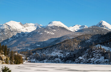 Whistler BC, Canada - December 12th, 2022:  A snow covered mountain range and frozen lake near...