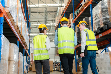 Three engineers inspecting goods in a large warehouse.