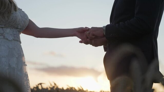 Slow motion shot of a wedding couple holding hands at sunset