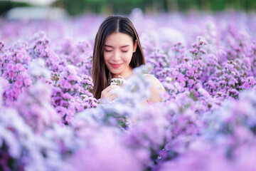 asian woman wearing white dress happily and smelling flowers in the flowers garden. travel relax on vacation concept..