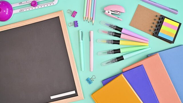 School stationery and blackboard moving on bright blue background. Copy space. Flat lay. Stop motion