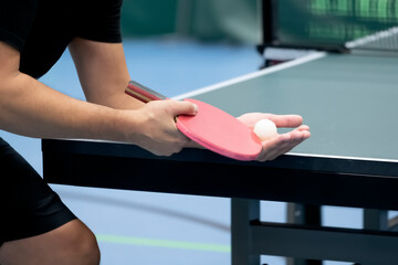 Table Tennis Player serving, holding ball in hand
