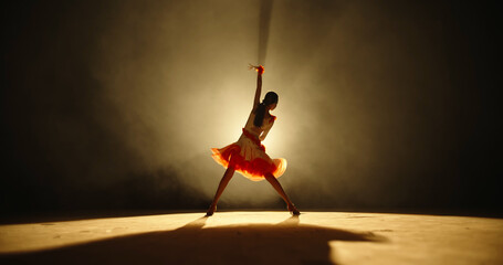 Talented asian female teenager is performing ballroom sport dance on stage with smoked black...