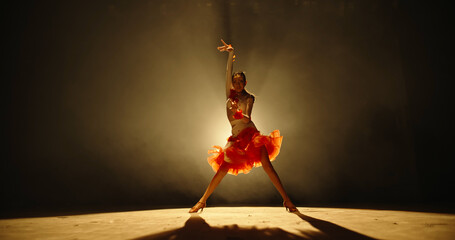 Talented asian female teenager is performing ballroom sport dance on stage with smoked black background - childhood dream, childhood memories concept 