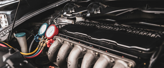 Car care maintenance and servicing, Close-up measuring manifold gauge on car engine for check refrigerant and filling air conditioner to fix repairing heat conditioning compressor system.