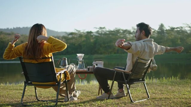 Young loving couple pretty while camp taking photo by smartphone while sitting at the camping and drinking a cup of coffee together on riverbank.outdoor lifestyle camping on holiday vacation concept