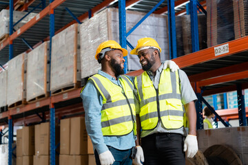 Two african workers talking and smiling in a warehouse.