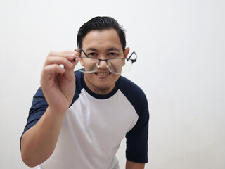 Portrait of Asian man smiling while adjusting his eyeglasses trying to see focus, eye sight trouble, blur vision