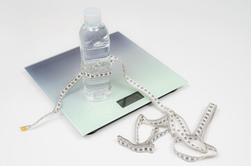 Weight scale, tape measure and water bottle isolated on white background