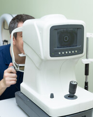 a man checks the vision of an ophthalmologist, a man does autorefractometry in the doctor's office,...