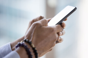 Close up African man holds smart phone. Unknown guy use modern cellphone, typing message in messenger, chatting in social media network, new mobile app for fun, easy fast delivery services. Tech usage