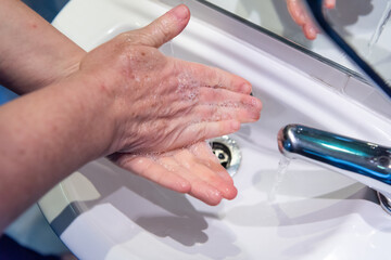 Washing hands with soap and water at basin