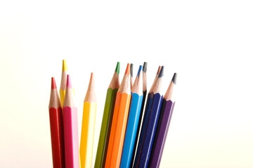 colored pencils against the background of a desk, notebook, white wall