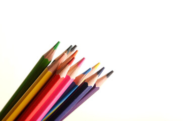 colored pencils against the background of a desk, notebook, white wall