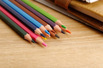 Obraz premium colored pencils against the background of a desk, notebook, white wall