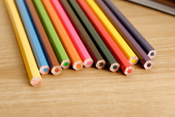 Obraz premium colored pencils against the background of a desk, notebook, white wall