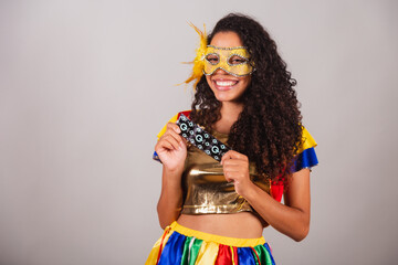 Beautiful black Brazilian woman, with frevo clothes, carnival. wearing a mask, holding a condom,...