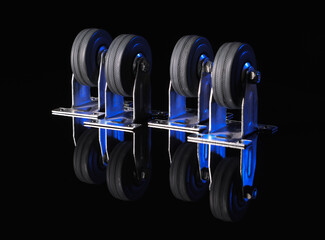 Rubber wheels in a metal frame on a black background with a reflection on the table
