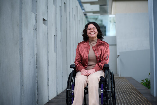 Smiling woman with a disability sitting in a wheelchair outside in urban setting