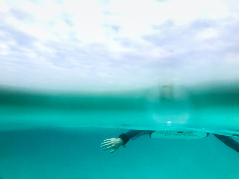 Split image of Arms paddling on boogie board underwater and overcast sky