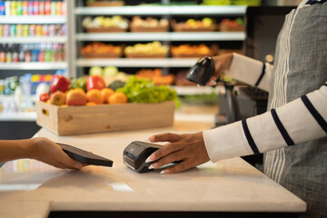 A customer shopping in a supermarket or retail shop, buying snacks and food in cashier on grocery products shelves with a basket. Food shopping. People lifestyle.  Checkout service