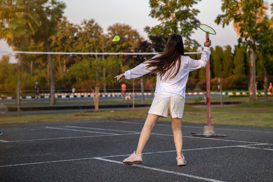 Woman Playing Badminton In The Park. Urban Asian Sporty Female Having Fun Outdoor Sports And Game Activity Concept