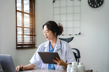 Doctor women working on laptop computer, writing prescription clipboard with record information...