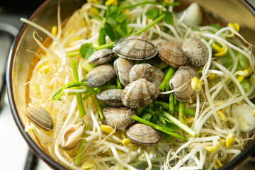 Clear clam soup boiling with vegetables in a pot	