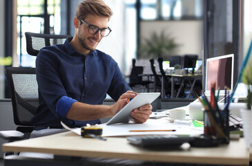 Young modern business man working using digital tablet while sitting in the office.