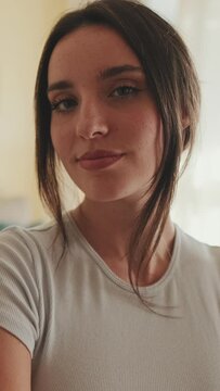 VERTICAL VIDEO, Close up, young beautiful woman crossing her arms and smiling at camera while standing at home