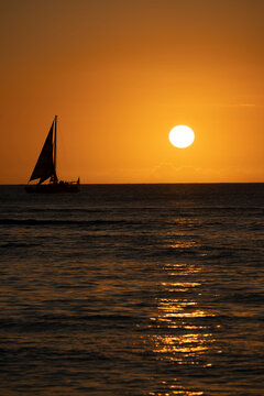 日没イメージ　海に沈む夕日とヨットのシルエット