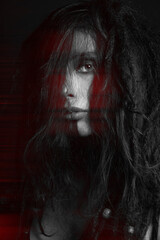Beautiful woman studio portrait in red color split effect. Model with dreadlocks covering her face with messy hair. Woman with make-up looking at camera. Futuristic looking style