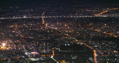 view of the night city of Chiang Mai from the top of the mountain at the time of the New Year, when fireworks explode at once and sky lanterns rise into the air
