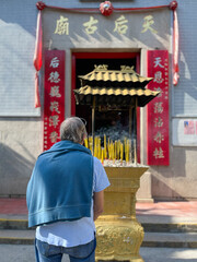 Caucasian man praying with incense at a Chinese Temple