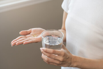 Dietary supplement, asian young woman hand holding fish oil or medical pill, take or eat vitamin C,...