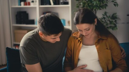 Excited young couple expecting baby, pregnant wife and husband touching belly