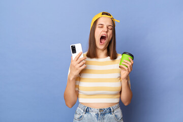 Horizontal shot of sleepy tired teen girl wearing striped T-shirt and baseball cap standing...