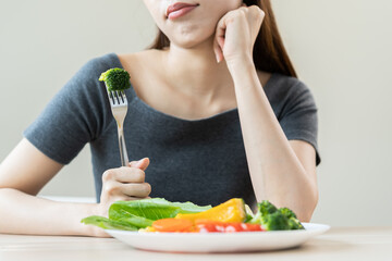 Diet in bored face, unhappy beautiful asian young woman, girl on dieting, holding fork in salad plate, dislike or tired with eat fresh vegetables. Nutrition of clean, healthy food good taste.