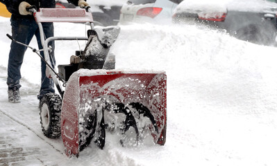 snowblower removes snow, a man cleans the yard outside