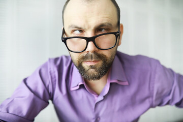 Obraz premium A cross-eyed bearded man is looking into the frame. Eye disease. The concept of an inexperienced specialist. Spy neighbor.