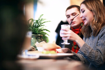 Couple in a restaurant or diner eating a hamburger and chicken wings flirting the while, shot with available light, very selective focus