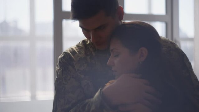 Sad military man hugging beloved woman before leaving for war in hot zone