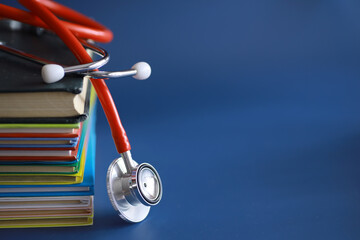 stethoscope on stack of medical guide book for doctor learning treatment at hospital. - obrazy, fototapety, plakaty