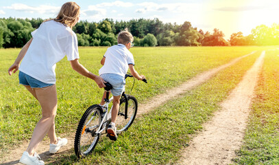 loving mother help her cute son ride a bicycle