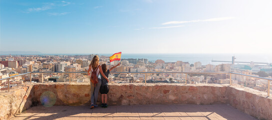 Mother and son holding Spain flag and looking at Almeria city panoramic
