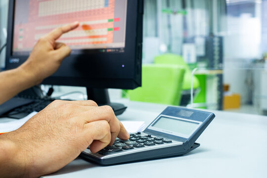 Man's hand is using calculator to do report work on computer, to present business earnings report, business and finance concept.