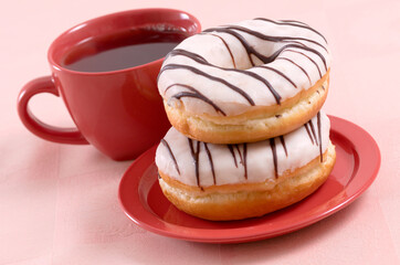 Glazed sweet doughnuts on red saucer and a cup of tea - 559361051